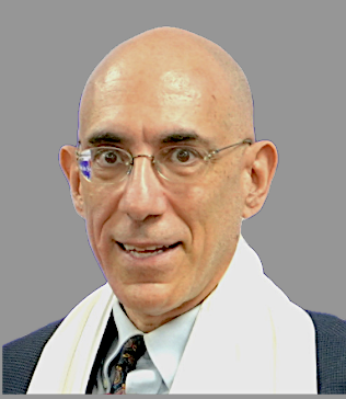 A bald man with glasses, wearing a suit, tie, and a white scarf, smiling slightly against a plain gray background.
